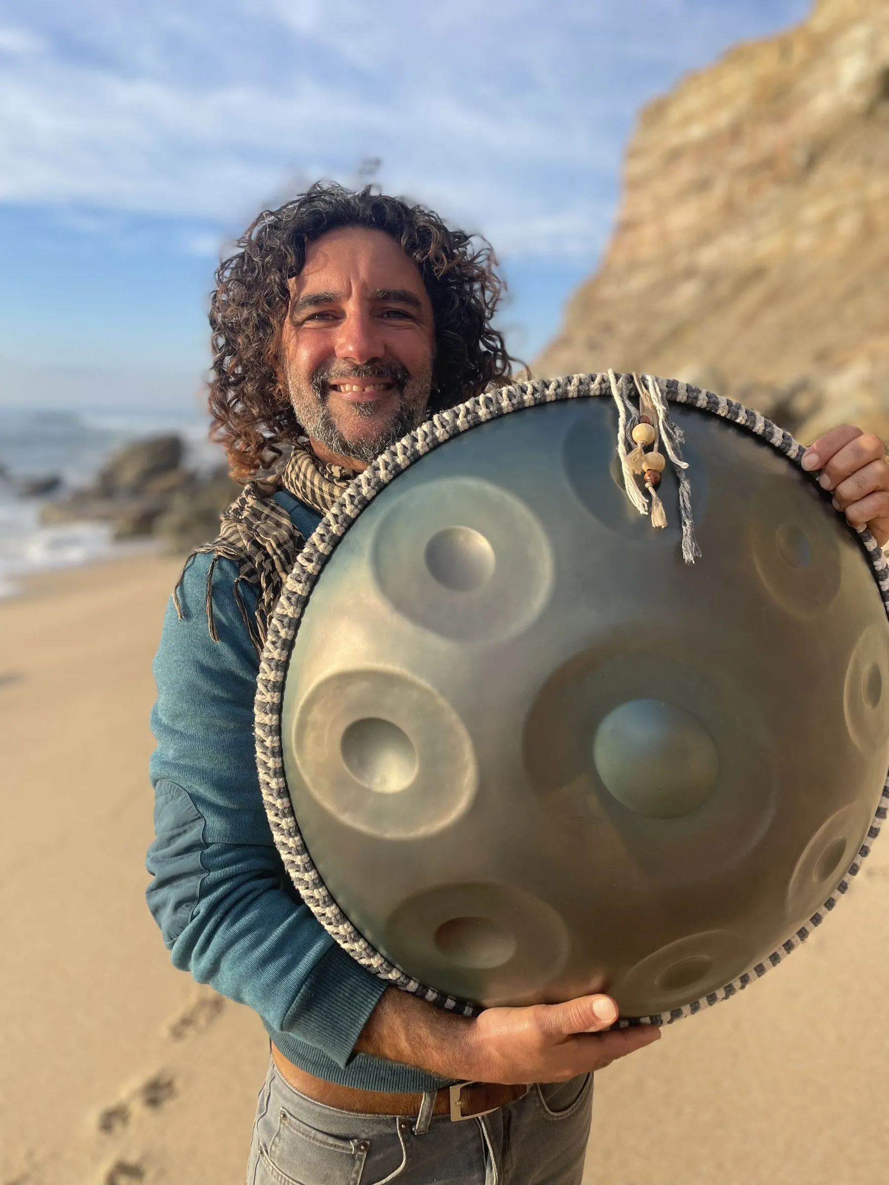 Peppi holding a handpan on the beach